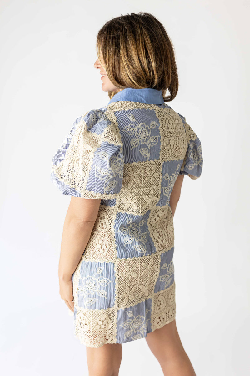 Back view of a woman wearing a boho patchwork crochet dress with blue and beige floral crochet patches