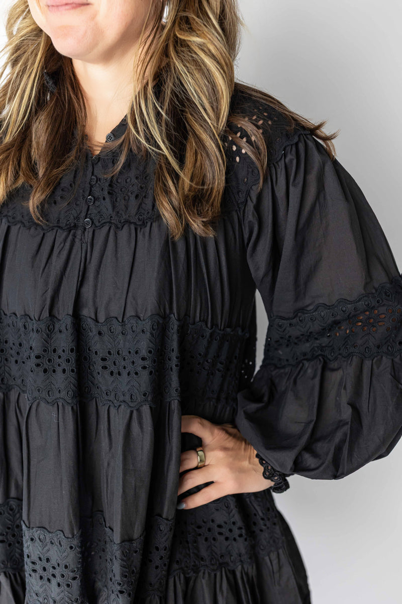 Close-up of black long sleeve eyelet mini dress with lace details and button front