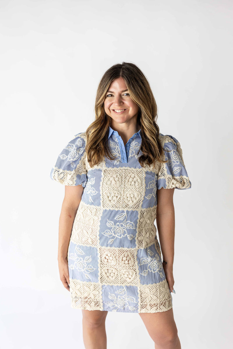 Woman wearing a blue and cream boho patchwork crochet dress with puff sleeves and floral patterns