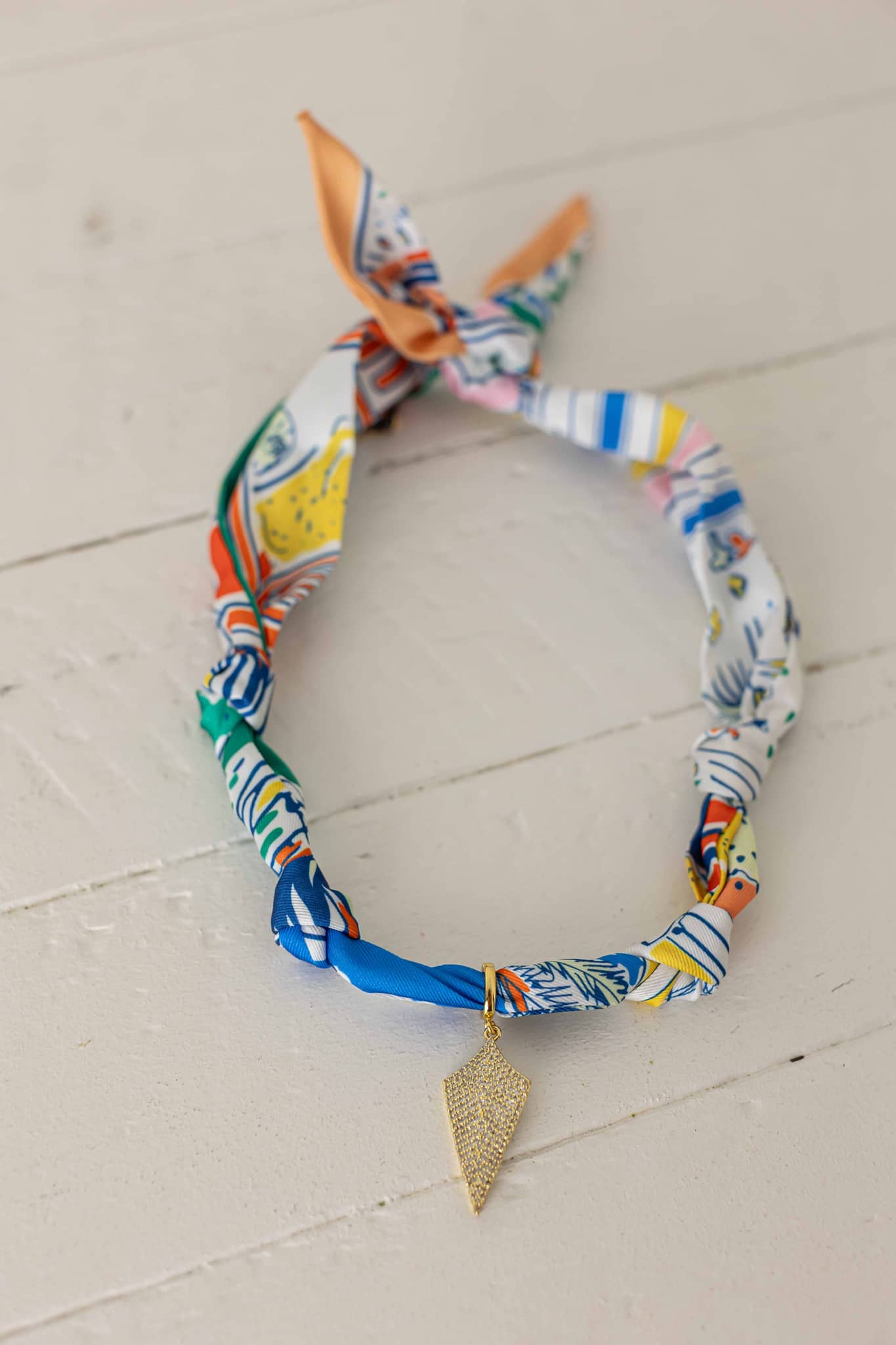 Weaving Color colorful fabric necklace with gold leaf pendant on white wooden background