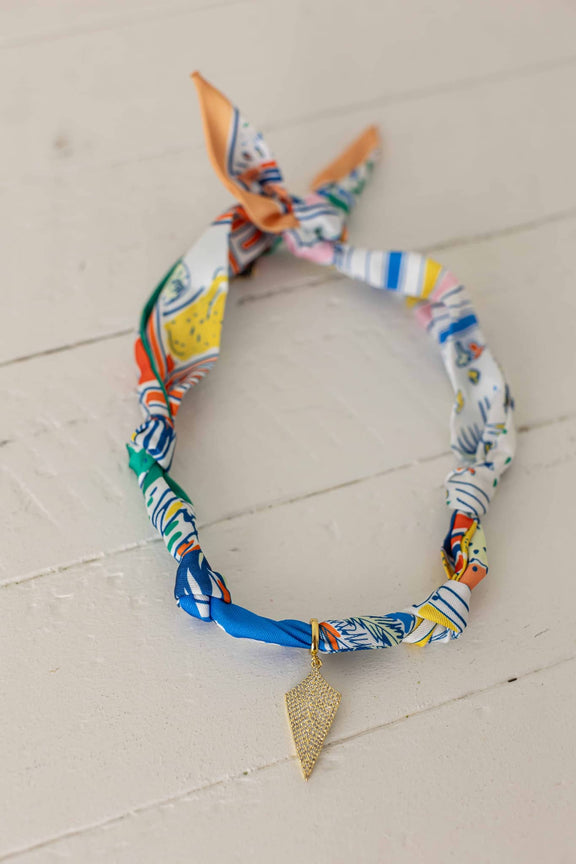 Weaving Color colorful fabric necklace with gold leaf pendant on white wooden background