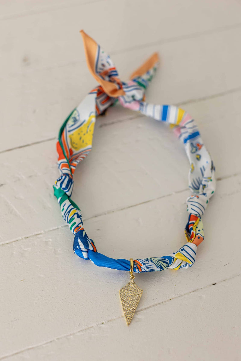 Weaving Color colorful fabric necklace with gold leaf pendant on white wooden background