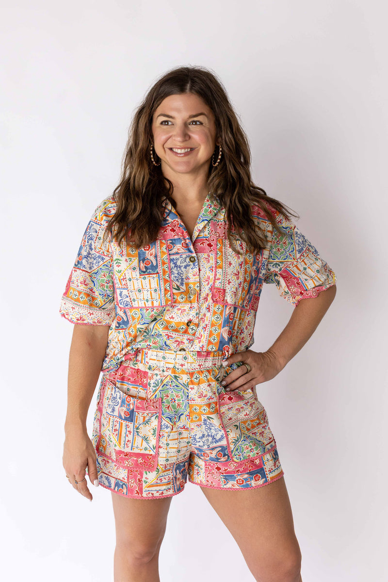 Woman wearing colorful patchwork shorts and matching short-sleeve button-up shirt by Weaving Color