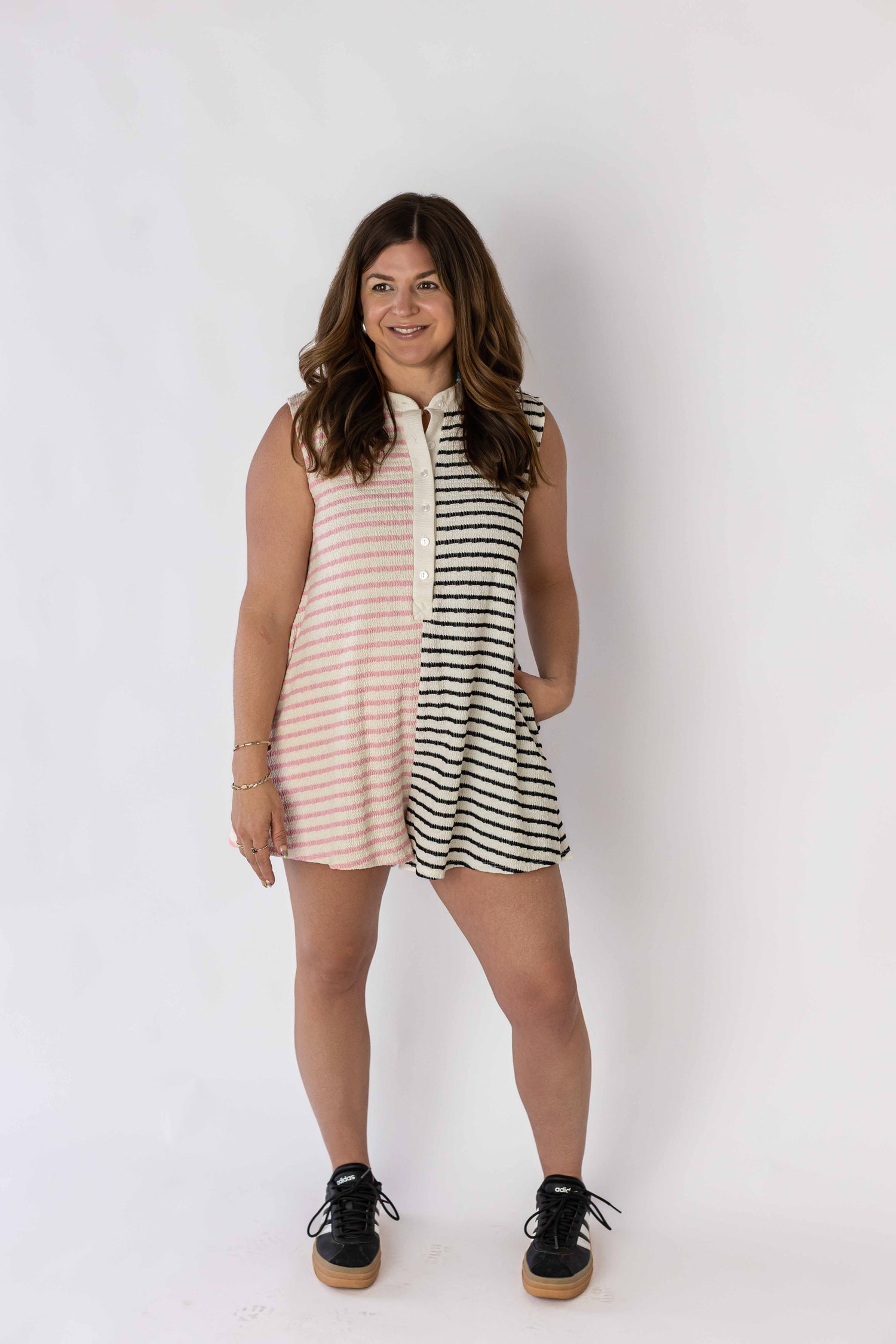 Woman wearing a sleeveless contrast stripe romper by Weaving Color with pink and black stripes