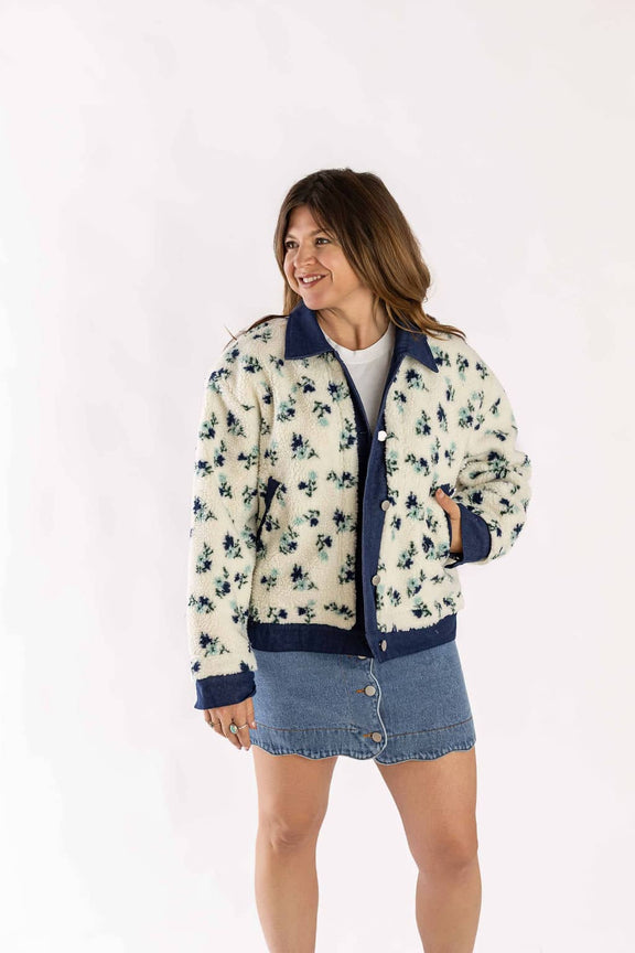 Woman wearing Weaving Color cropped dad sherpa trucker jacket with floral pattern and denim skirt