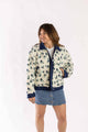 Woman wearing Weaving Color cropped dad sherpa trucker jacket with floral pattern and denim skirt