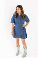 Woman wearing a blue denim dress by Weaving Color with short sleeves and side tie detail