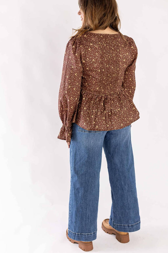 Woman wearing blue trouser wide leg pants paired with a brown floral long sleeve top