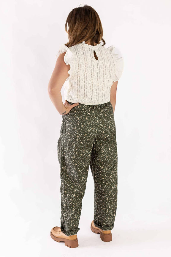 Back view of woman wearing Weaving Color floral print drawstring pants with white ruffled sleeve top