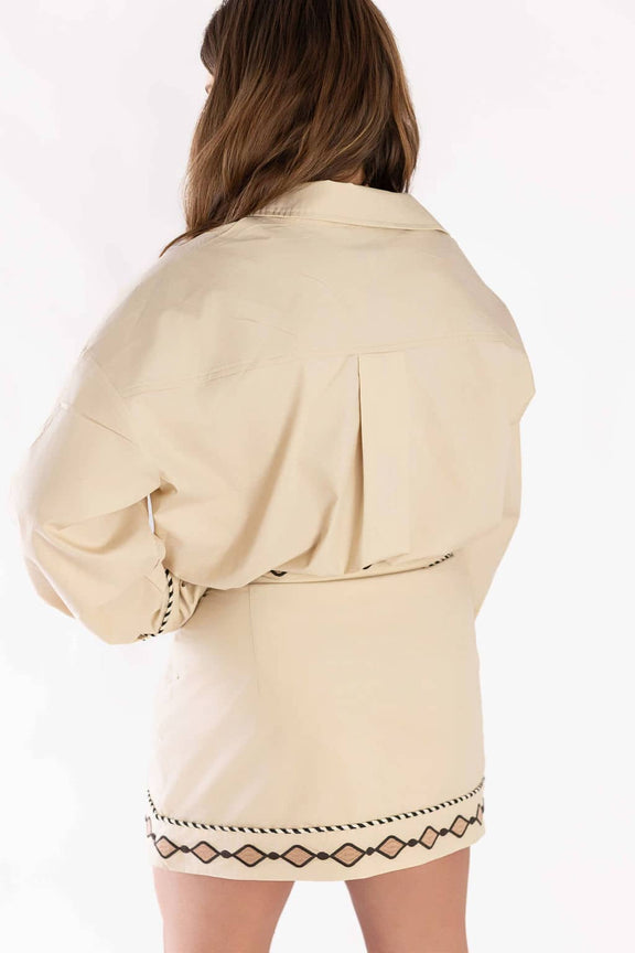 Back view of woman wearing beige Weaving Color embroidered set with black geometric patterns on skirt and sleeves