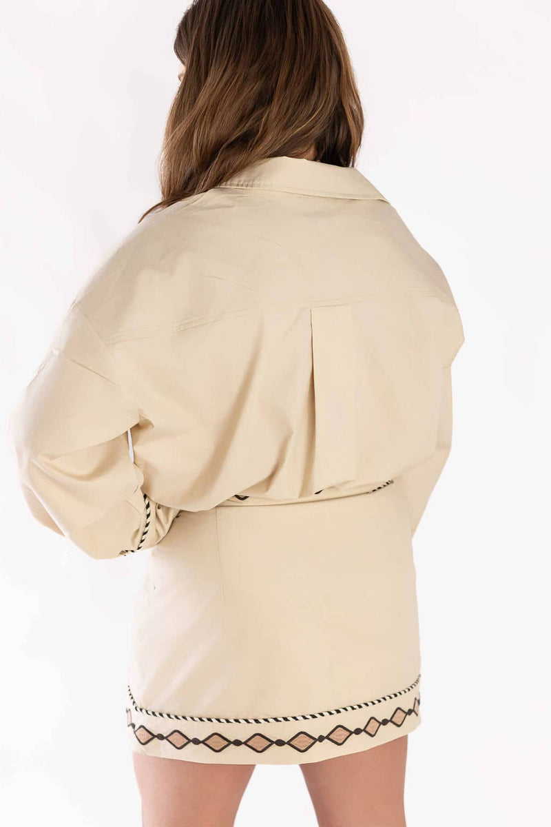 Back view of woman wearing beige Weaving Color embroidered set with black geometric patterns on skirt and sleeves