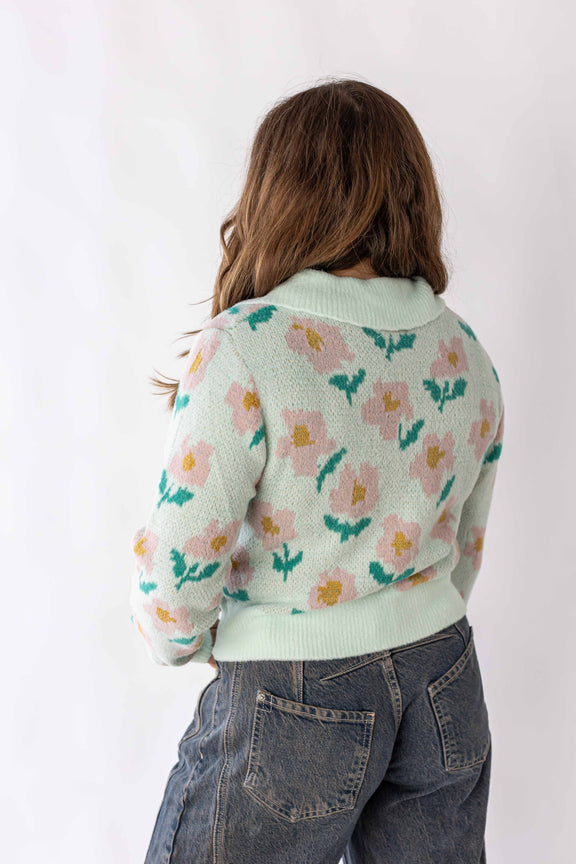 Back view of a woman wearing a floral detail sweater with pastel green and pink flowers by Weaving Color