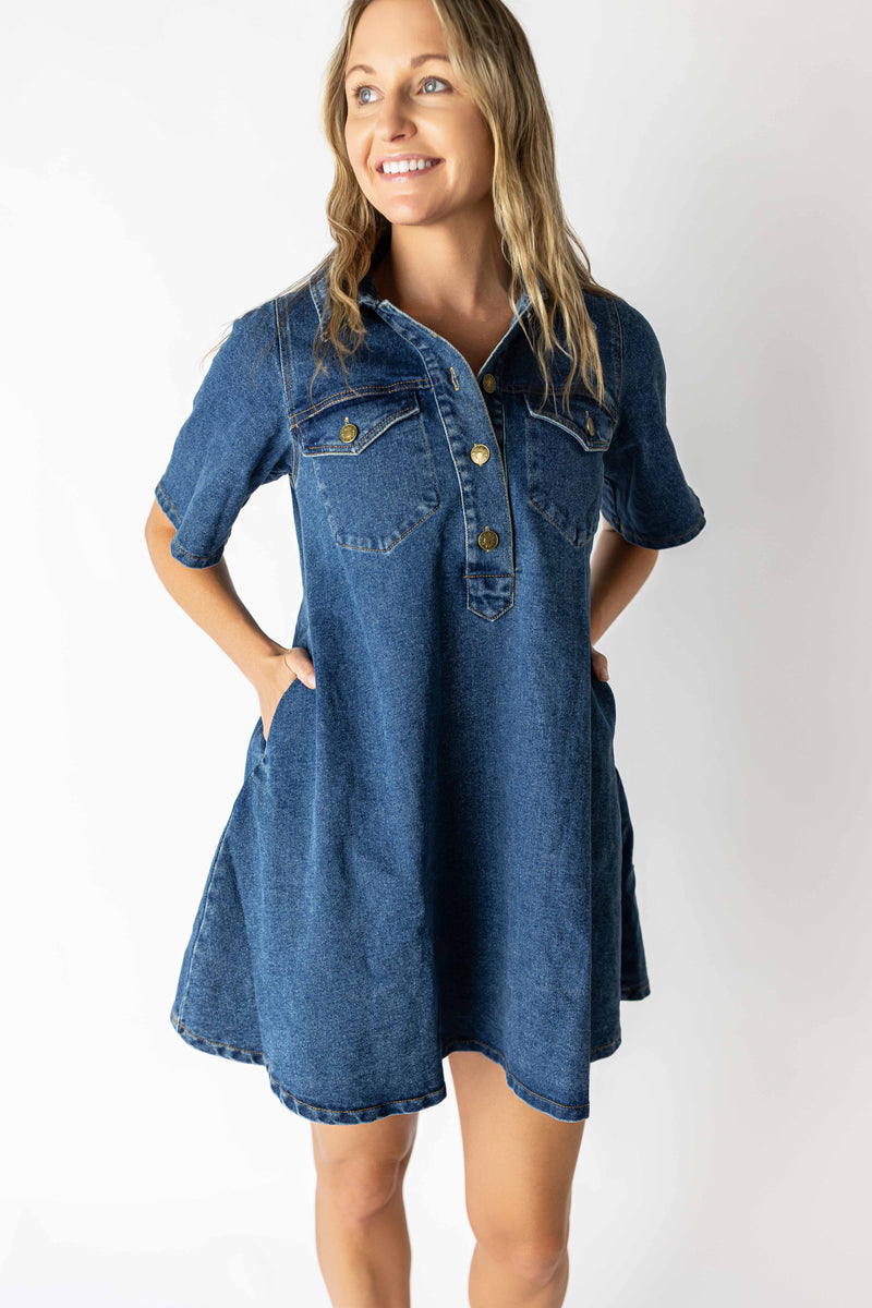 Woman wearing a medium wash denim dress with short sleeves and front button details