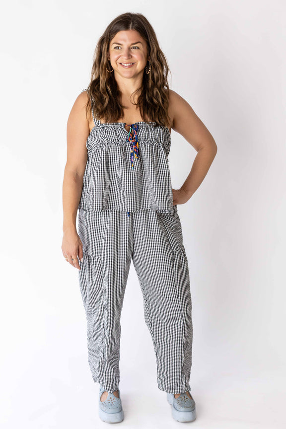 Woman wearing black and white gingham relaxed pants and matching sleeveless top with casual shoes