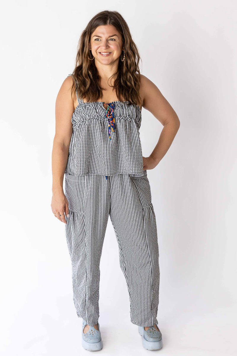 Woman wearing black and white gingham relaxed pants and matching sleeveless top with casual shoes