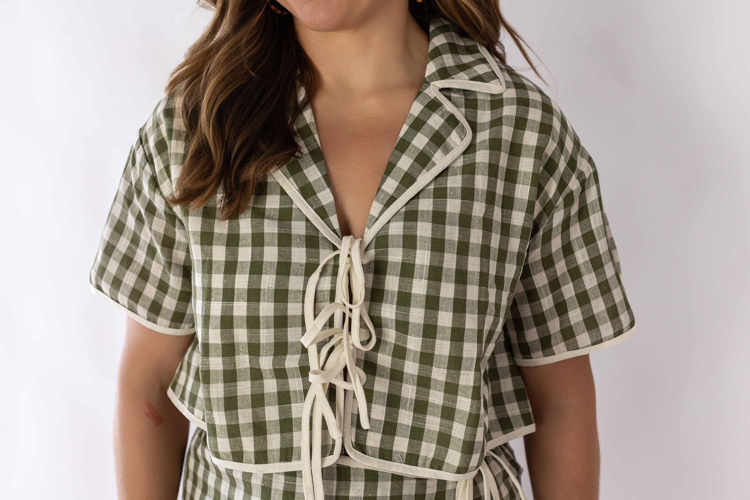 Close-up of woman wearing green and white gingham skort set with short sleeves and tie front