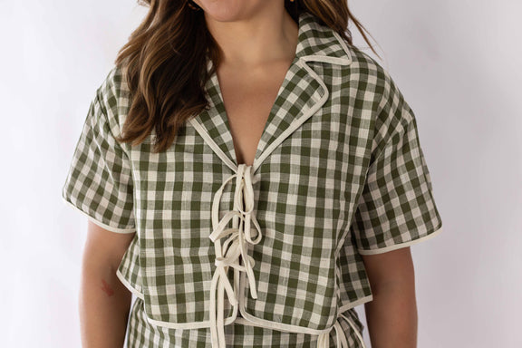 Close-up of woman wearing green and white gingham skort set with short sleeves and tie front