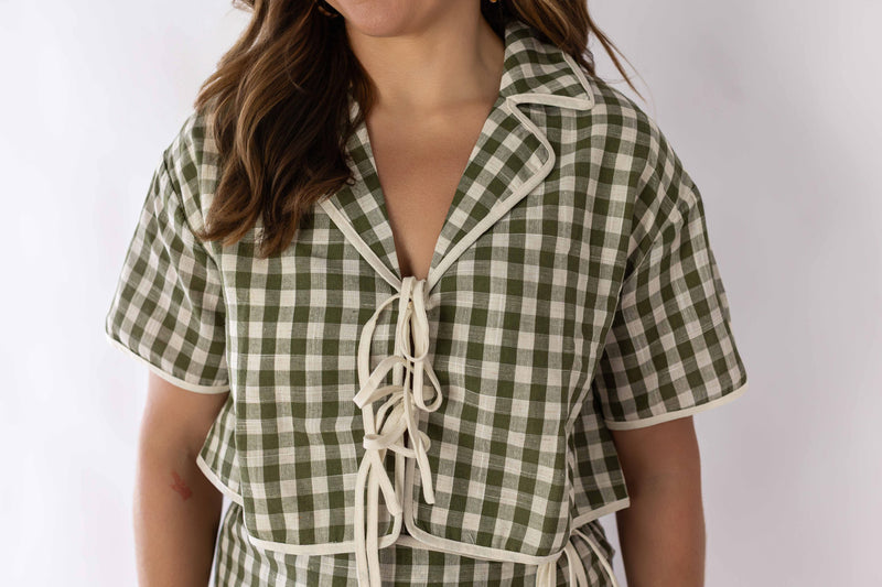 Close-up of woman wearing green and white gingham skort set with short sleeves and tie front