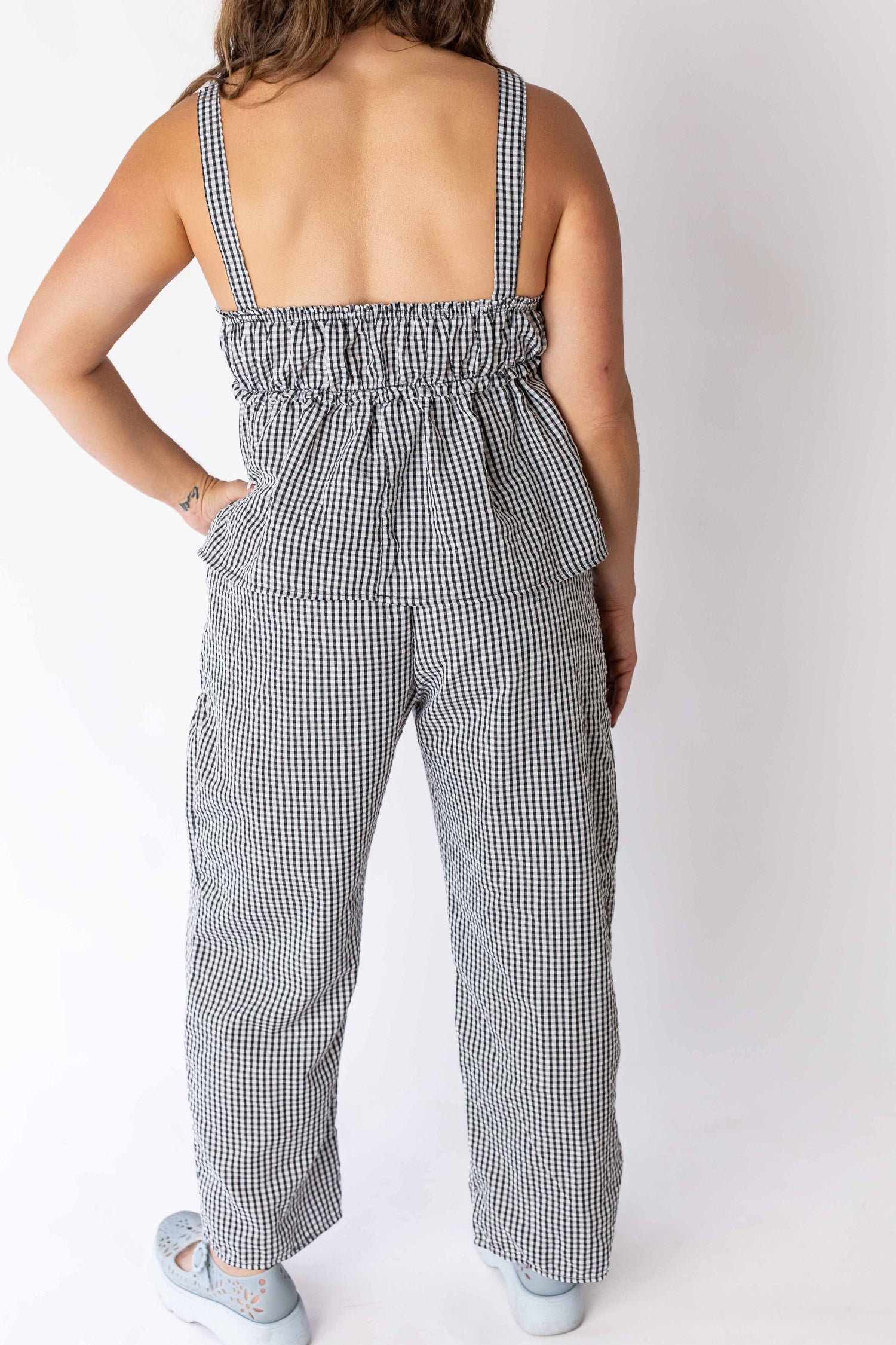 Back view of woman wearing black and white gingham tie front top with matching pants from Weaving Color