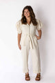 Woman wearing ivory puff sleeve jumpsuit by Weaving Color with belt and zipper front