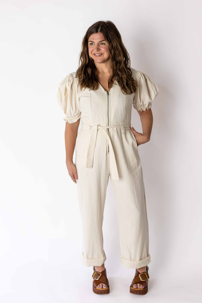 Woman wearing ivory puff sleeve jumpsuit by Weaving Color with belt and zipper front