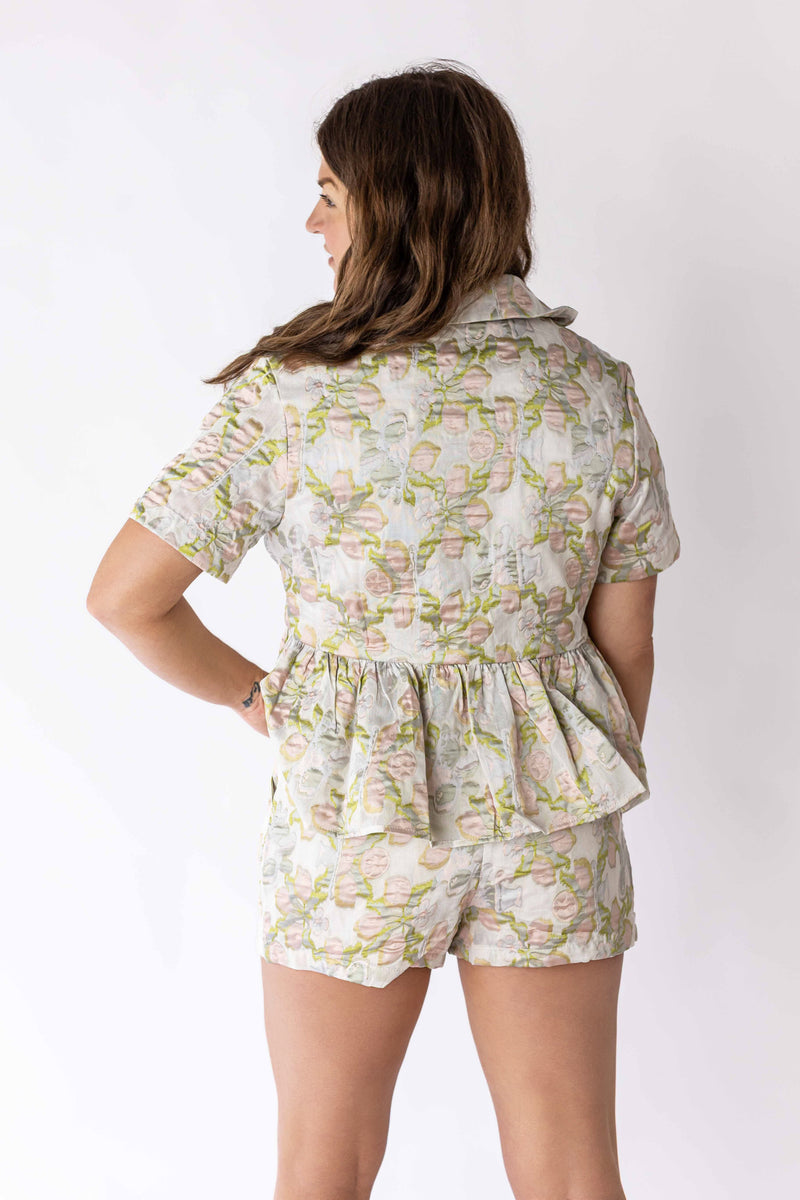 Back view of woman wearing Weaving Color jacquard belted shorts with floral pattern and matching top