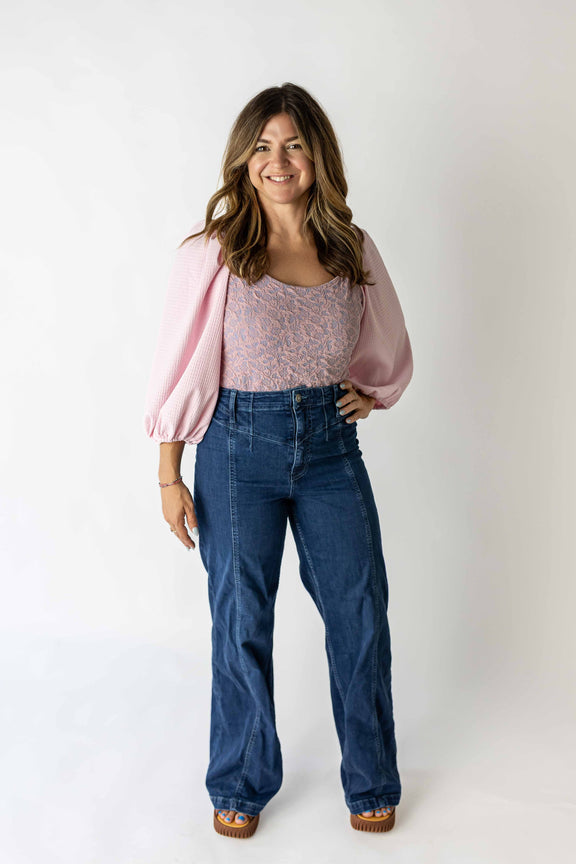 Woman wearing a lavender puff sleeve bodysuit paired with high-waisted blue jeans and brown shoes
