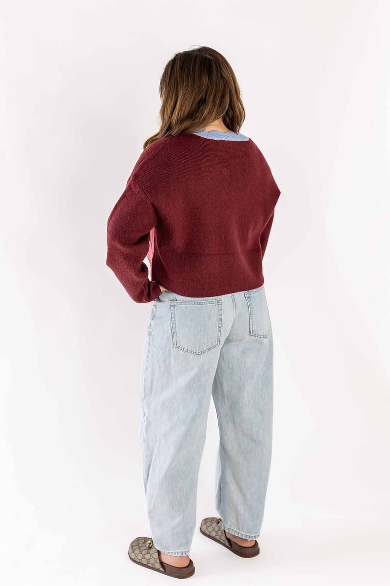 Woman wearing Weaving Color light wash blue jeans with a red sweater and patterned slip-on shoes