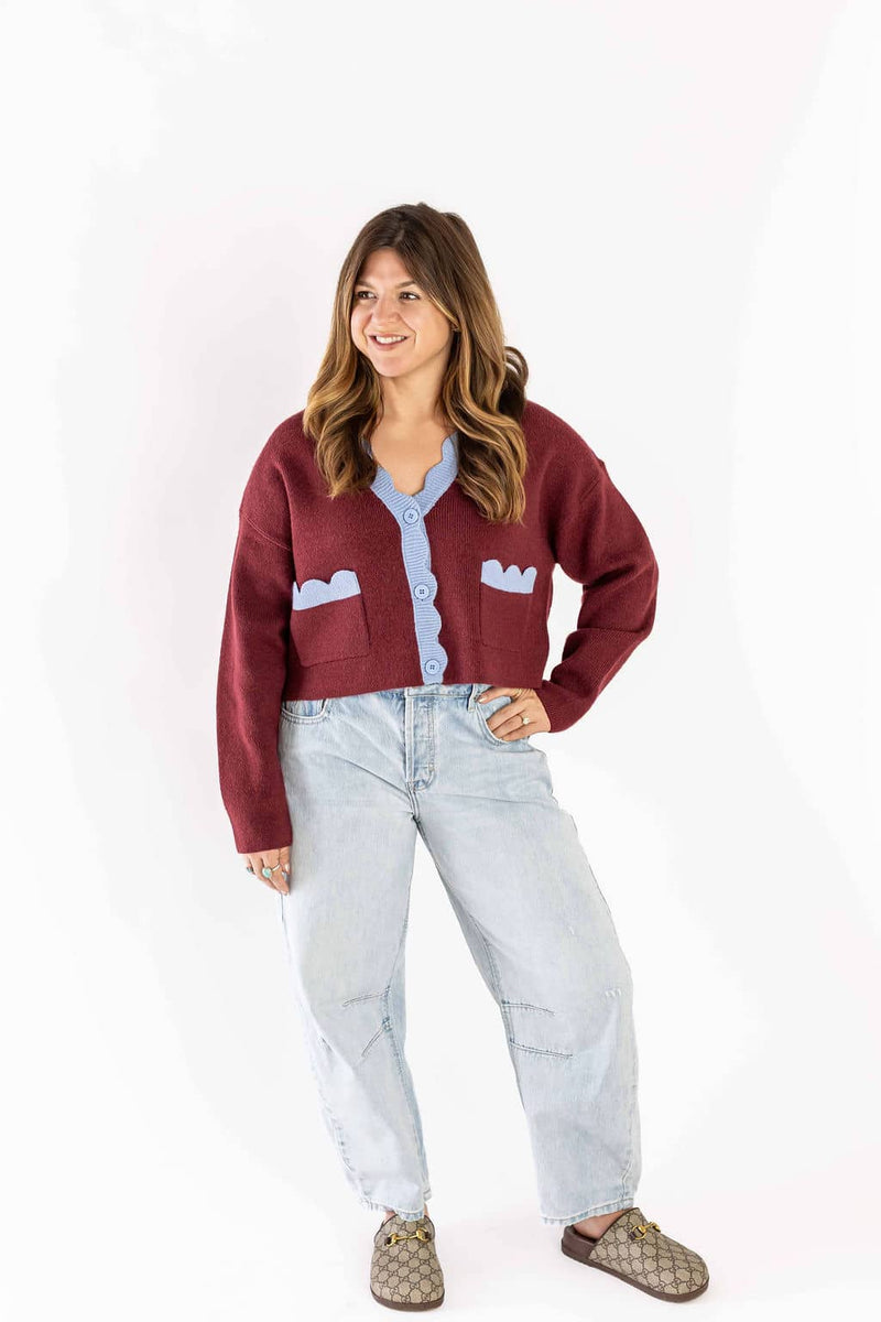 Woman wearing Weaving Color light wash blue jeans paired with a maroon and blue cardigan