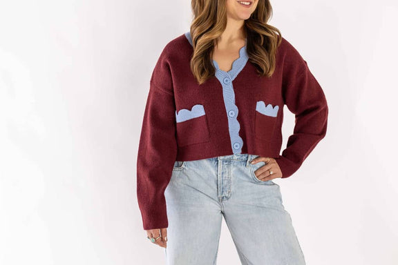 Woman wearing light wash blue jeans paired with a burgundy and light blue buttoned cardigan