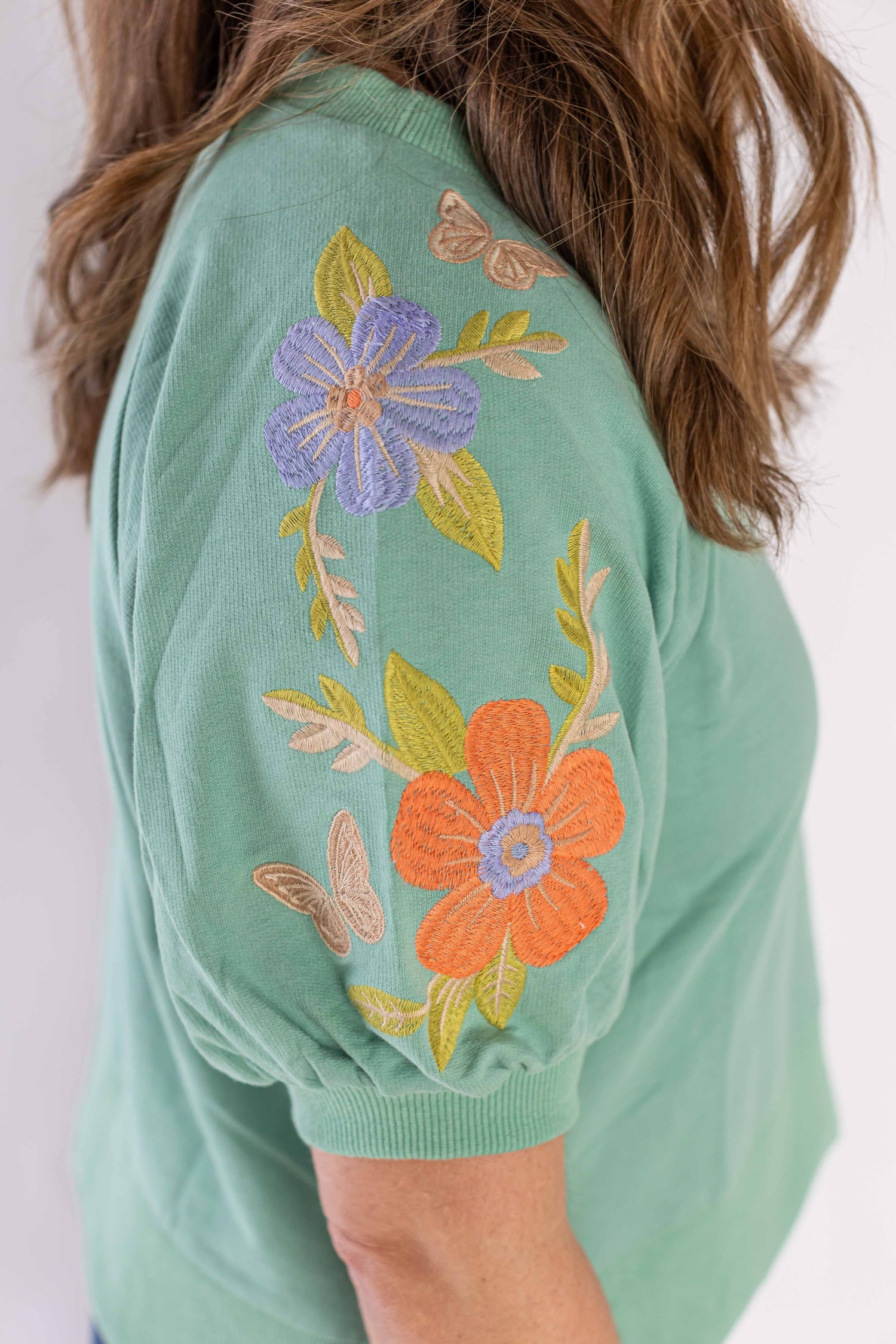 Weaving Color mineral bloom sweatshirt with green fabric and embroidered floral designs on sleeve