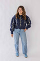 Woman wearing Weaving Color navy blue daisy chain sweater with floral embroidery and light blue jeans