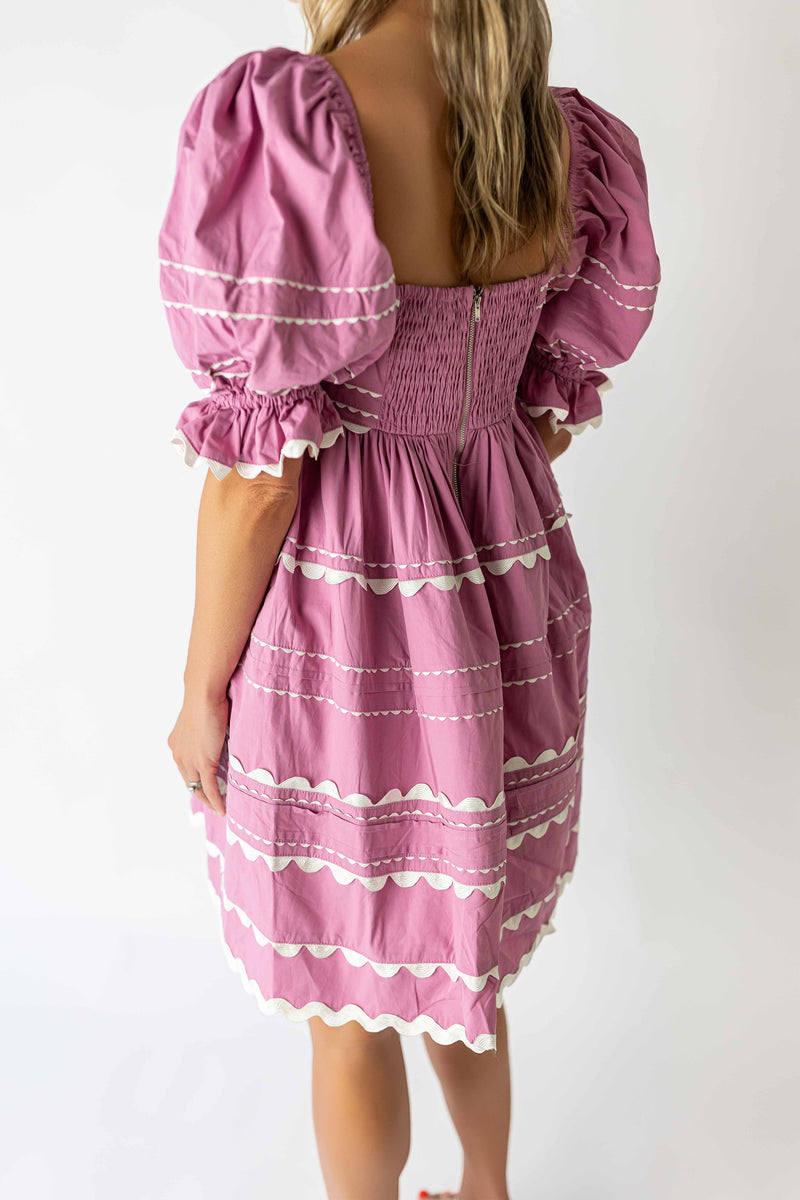 Back view of pink puff sleeve mini dress with smocked bodice and white scalloped trim