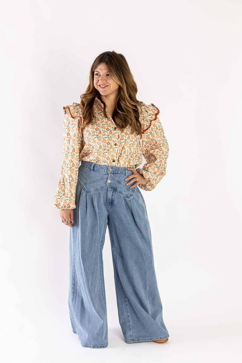 Woman wearing Weaving Color floral ruffle blouse paired with high-waisted wide-leg jeans