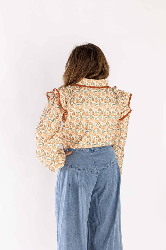 Back view of woman wearing Weaving Color ruffle blouse with floral pattern and blue wide-leg jeans