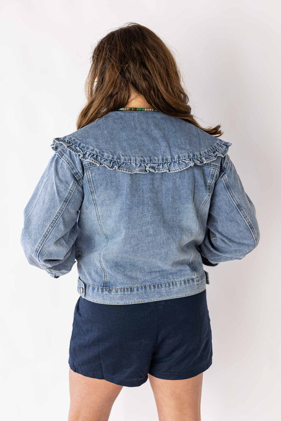 Back view of woman wearing ruffle collar denim jacket by Weaving Color with puff sleeves and light wash