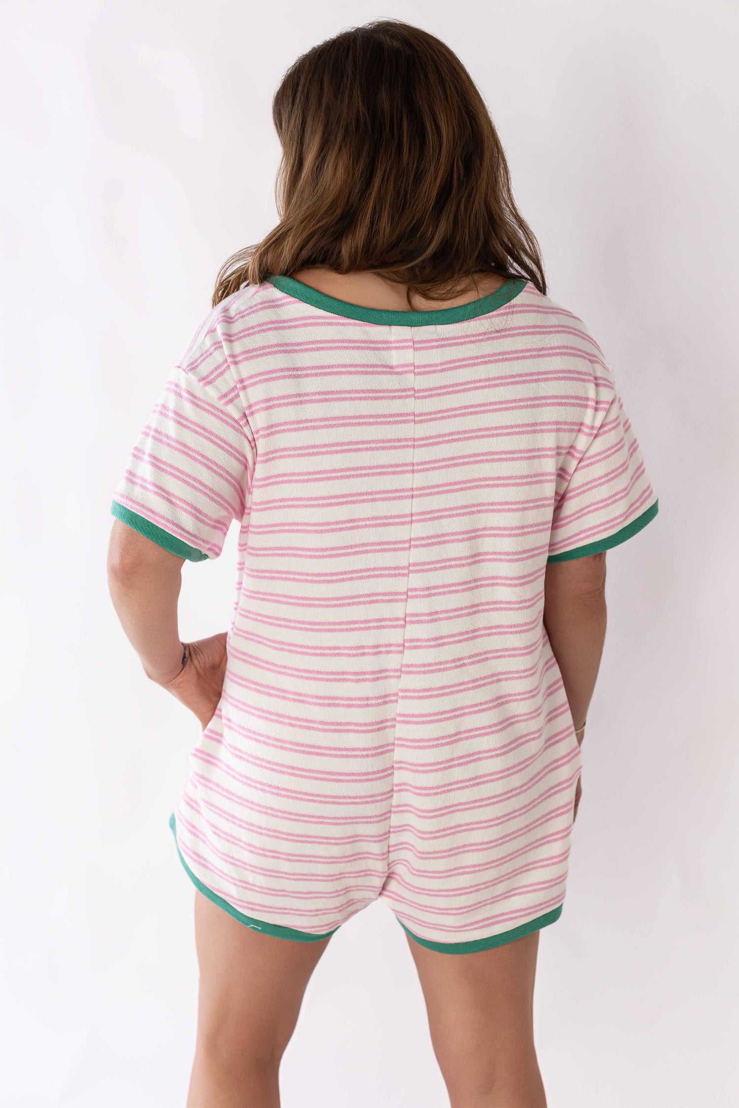 Back view of striped terry romper for women with pink and white stripes and green trim on sleeves and neckline