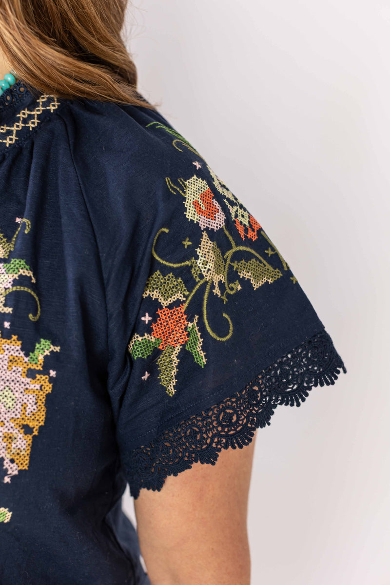 Close-up of embroidered bloom romper sleeve with floral embroidery and lace trim by Weaving Color