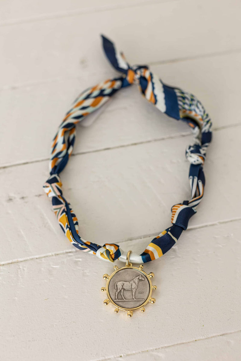 Weaving Color scarf necklace with blue and orange patterned fabric and gold pendant featuring an elephant design