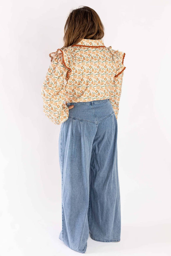 Back view of woman wearing Weaving Color wide-leg jeans paired with a floral ruffled blouse