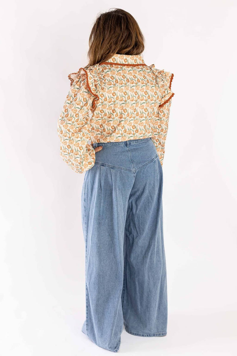 Back view of woman wearing Weaving Color wide-leg jeans paired with a floral ruffled blouse