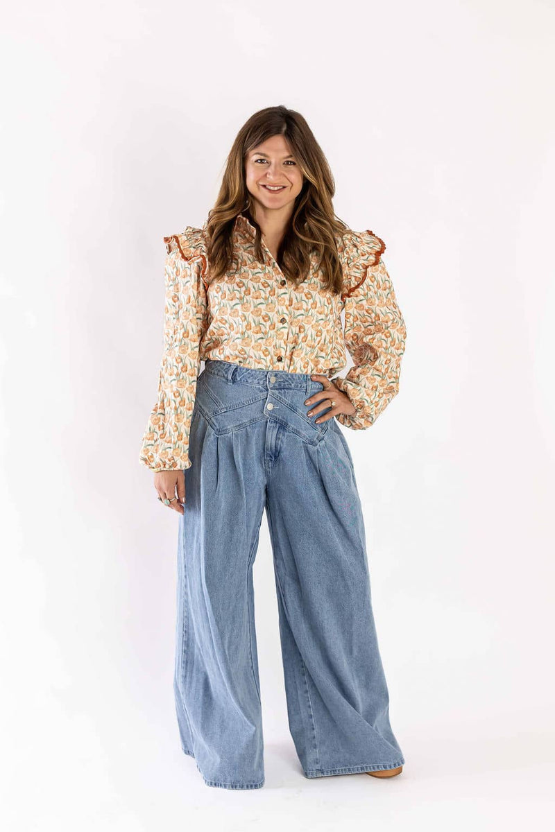 Weaving Color floral ruffle blouse with long sleeves worn by woman paired with wide-leg jeans